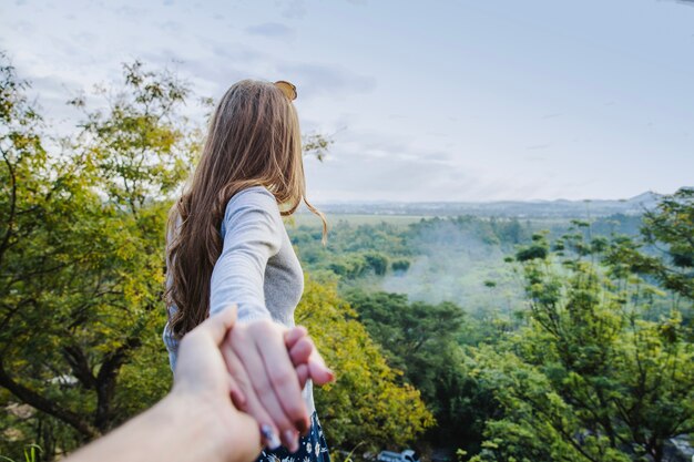 Girl pulling boyfriends hand in countryside