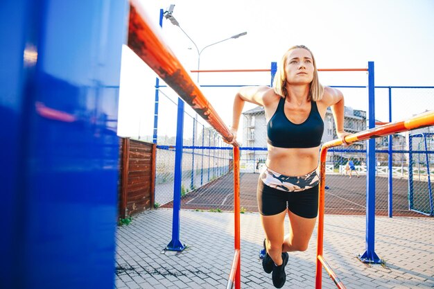 Girl pulling up with crossed legs on bars