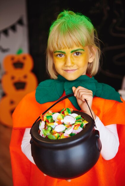 Girl in pumpkin costume holding a bowl full of candies