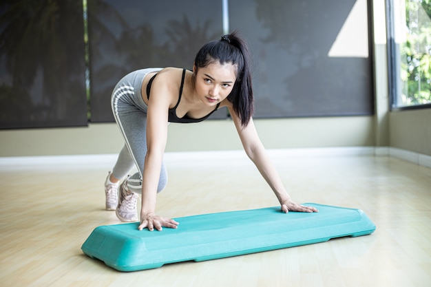 La ragazza spinse verso l'alto con la piattaforma di passi in palestra.