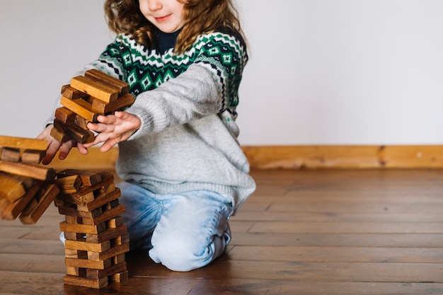 Девушка толкает штабелированные деревянные блоки