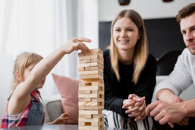 両親の近くの塔の上にブロックを置く少女