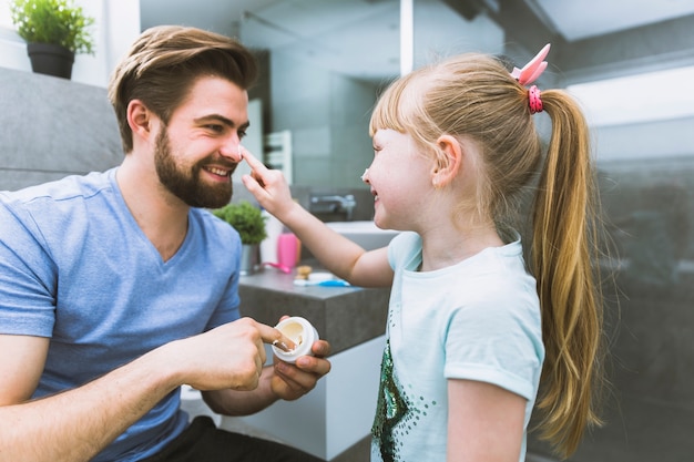 Free photo girl putting cream on nose of father