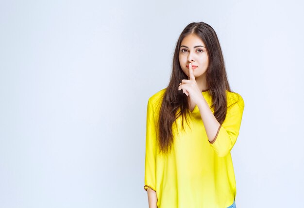 Girl putting finger to her mouth and asking for silence.