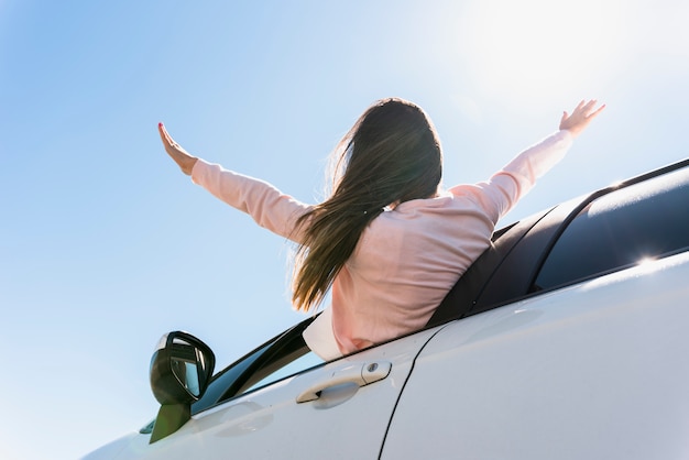 彼女の頭を窓の車の外に置いている少女