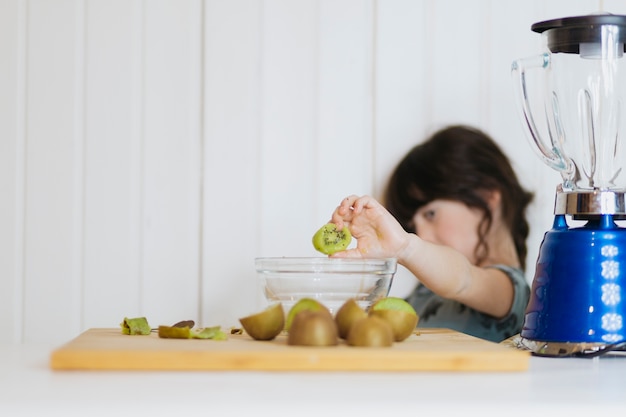 Girl putting kiwifruit to bowl