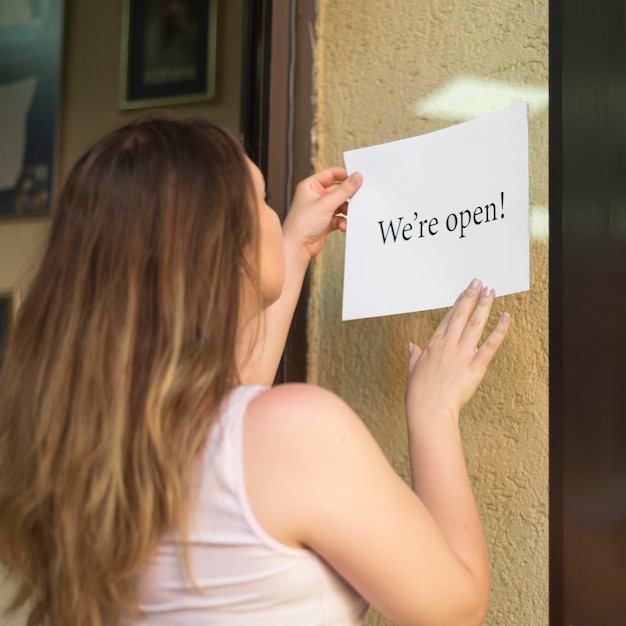 Free photo girl putting a we're open sign after the end of quarantine