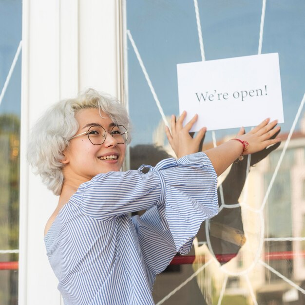 Girl putting a we're open sign on a door