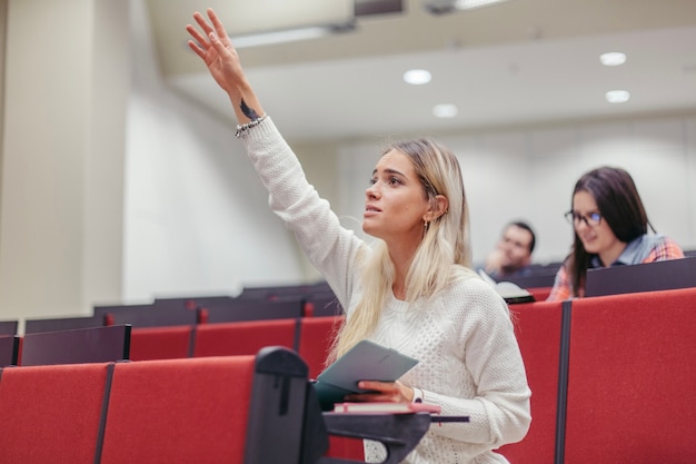 Девушка поднимает руку в лекционный зал