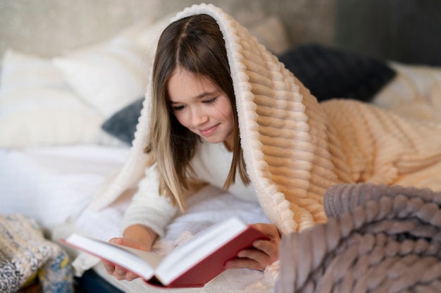 Foto gratuita ragazza che legge a letto inquadratura media