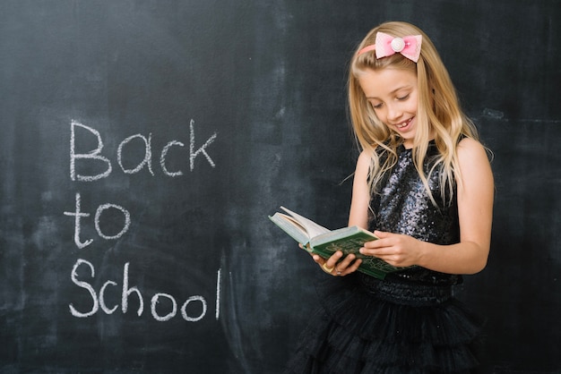 Girl reading book at blackboard