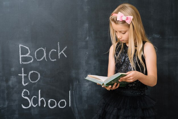 Girl reading book at chalkboard