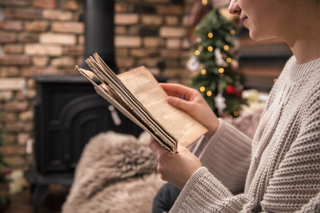 Free photo girl reading a book in a cozy home atmosphere near the fireplace, close-up