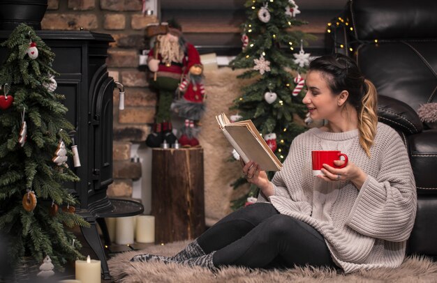 girl reading a book in a cozy home atmosphere near the fireplace