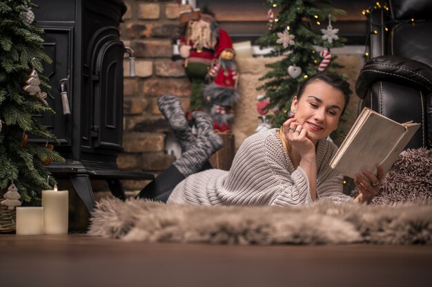 girl reading a book in a cozy home atmosphere near the fireplace