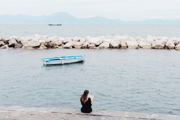 Girl reading a book at the dock