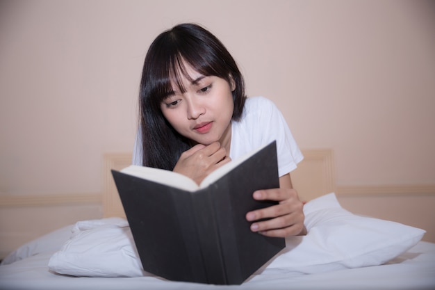 girl reading book and drinking coffee in bed in the morning