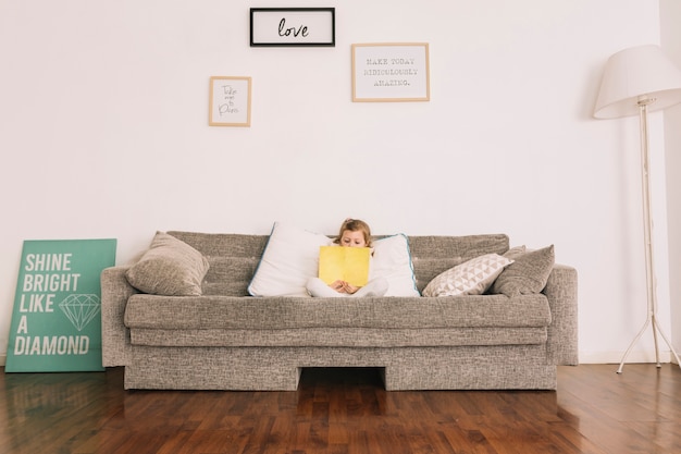 Girl reading book on soft couch