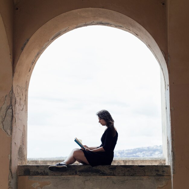 Girl reading a book on a window