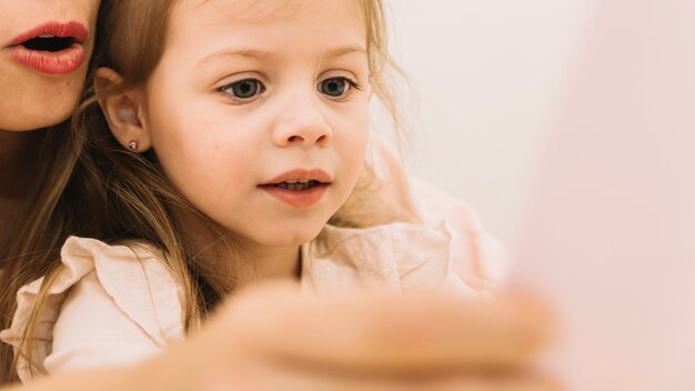 Girl reading book with anonymous mother