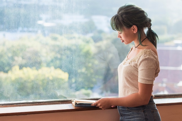 Free photo girl reading in front of a window