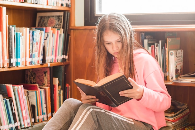 Foto gratuita ragazza che legge in biblioteca