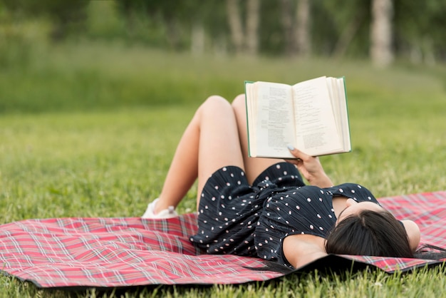 Foto gratuita ragazza che legge su una coperta da picnic