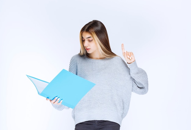 Girl reading the reports on the blue folder and making remarks.