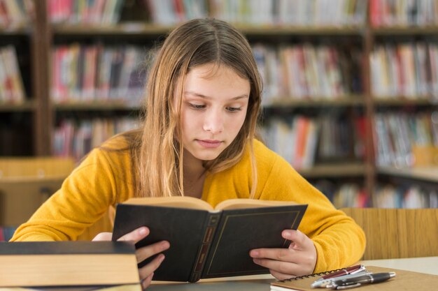 Девочка читает в школьной библиотеке