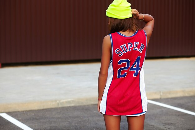 girl in red basketball sports clothes sitting on asphalt