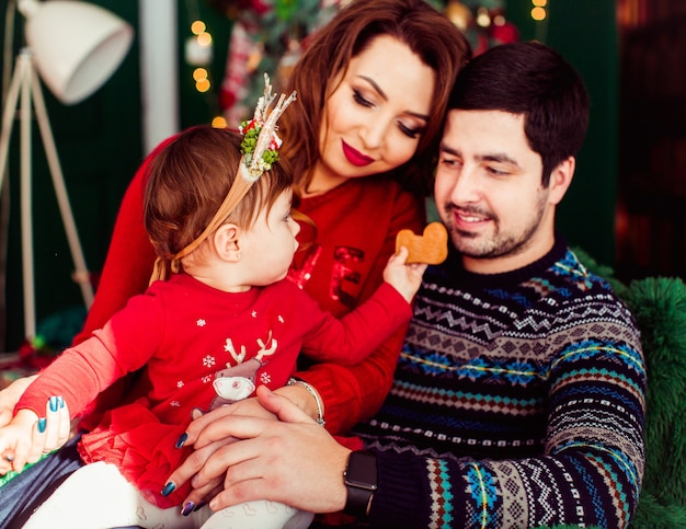 Girl in red dress reaches out hand with cookie to her father 