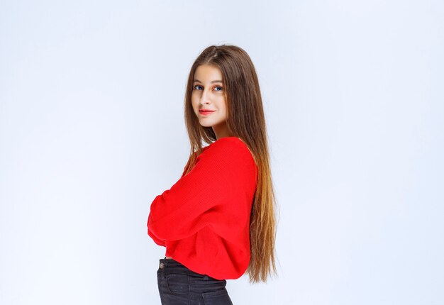 Girl in red shirt crossing arms and giving poses from profile. 