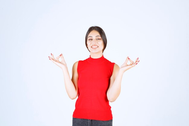 Girl in red shirt doing meditation.