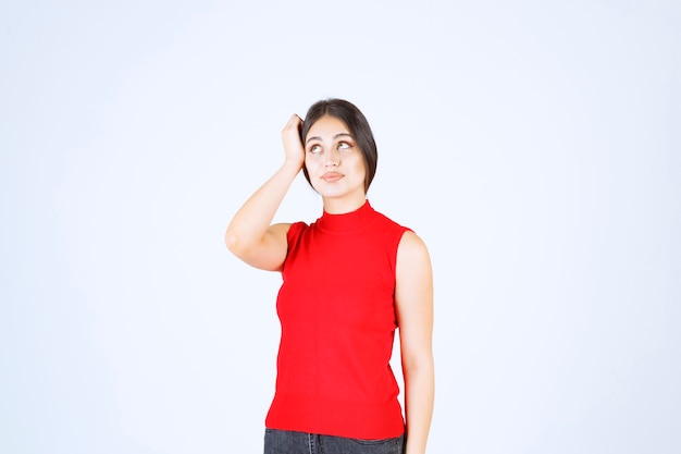 중립적이고 긍정적이며 매력적인 포즈를 취하는 빨간 셔츠의 소녀.