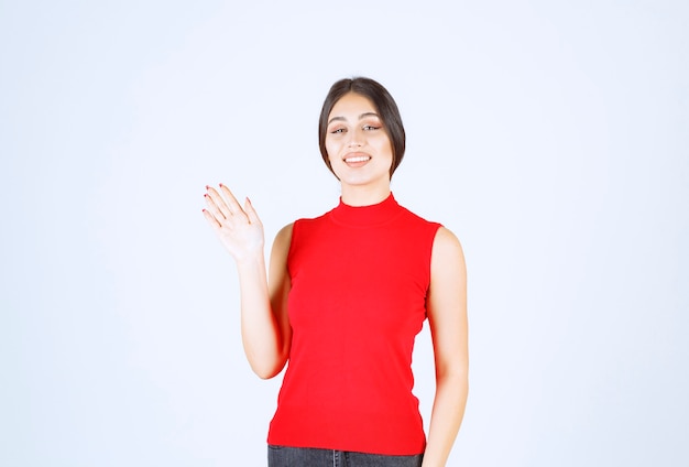 Girl in red shirt greeting or inviting someone.