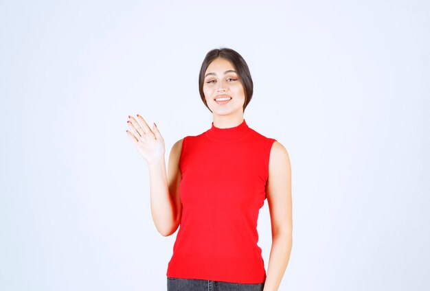 Girl in red shirt greeting or inviting someone.