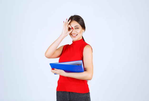 Girl in red shirt holding a blue business folder.