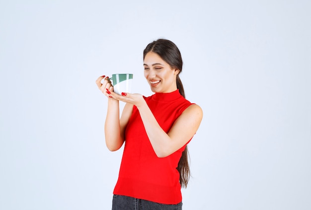 Girl in red shirt holding a coffee mug.