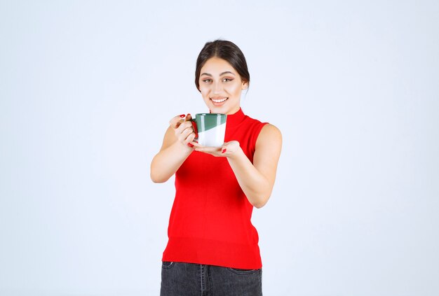 커피 잔을 들고 빨간색 셔츠에 소녀입니다.