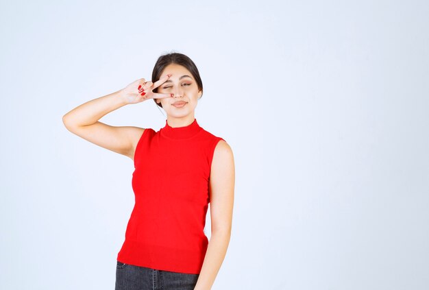 Ragazza in camicia rossa che guarda tra le dita.