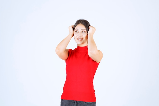 Girl in a red shirt looks scared and terrified.