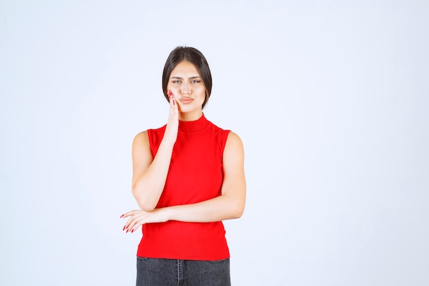 Girl in a red shirt looks scared and terrified.