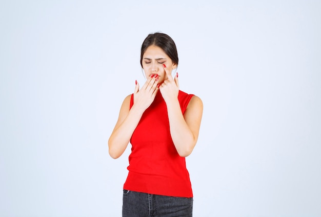 Girl in red shirt looks tired and sleepy.