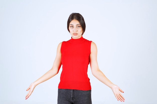 Ragazza in camicia rossa che fa il viso fastidioso e noioso.