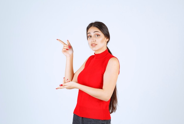 Girl in a red shirt pointing to the left side.