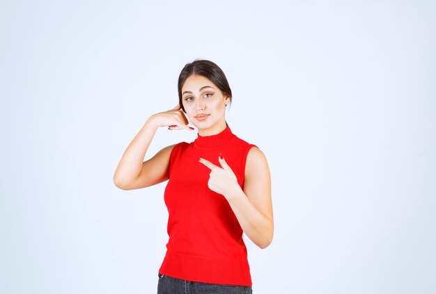 Girl in a red shirt pointing to the left side.