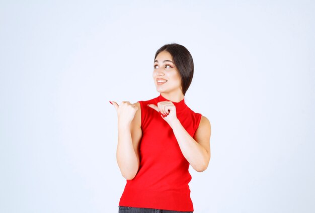 Girl in red shirt pointing at something on the left.