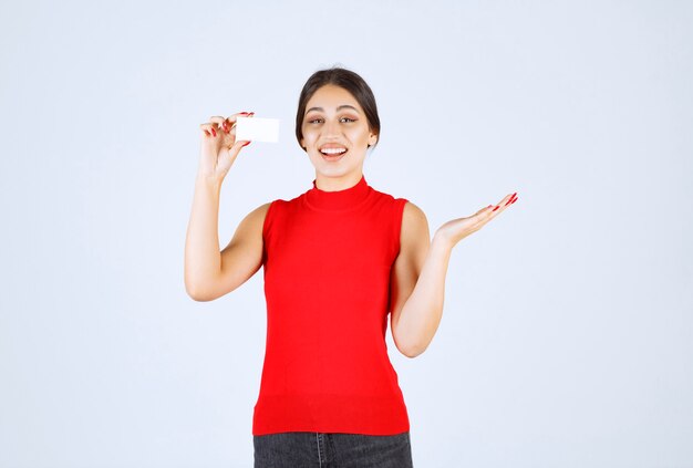 그녀의 명함을 제시하는 빨간 셔츠에있는 여자.
