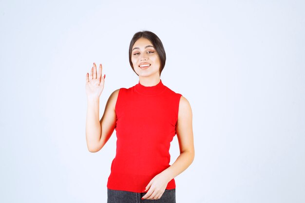 Девушка в красной рубашке поднимает руку и указывает выше.