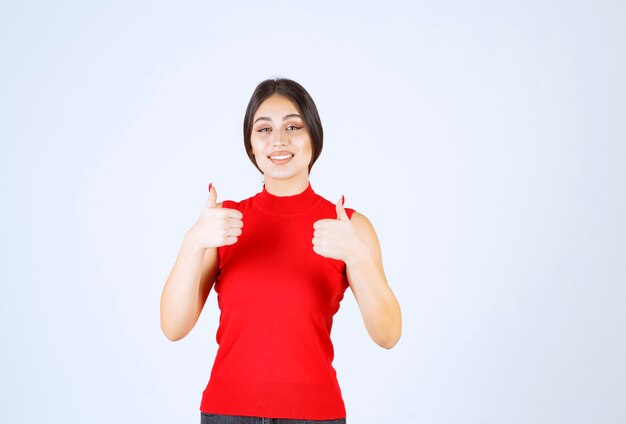 Girl in red shirt showing enjoyment hand sign.